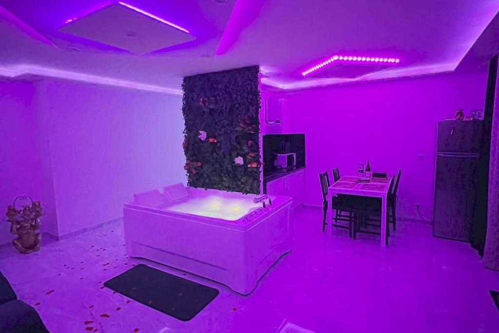 a room with pink lights and a table and a tub at Golden seconds in Strasbourg