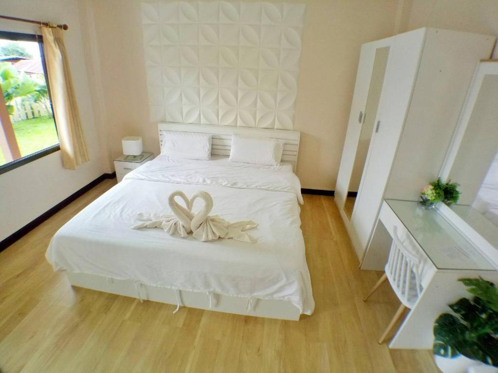 um quarto com uma cama branca com um laço em โรงแรมเรือนไทย 1 (Thai Guest House) em Ban Don Klang