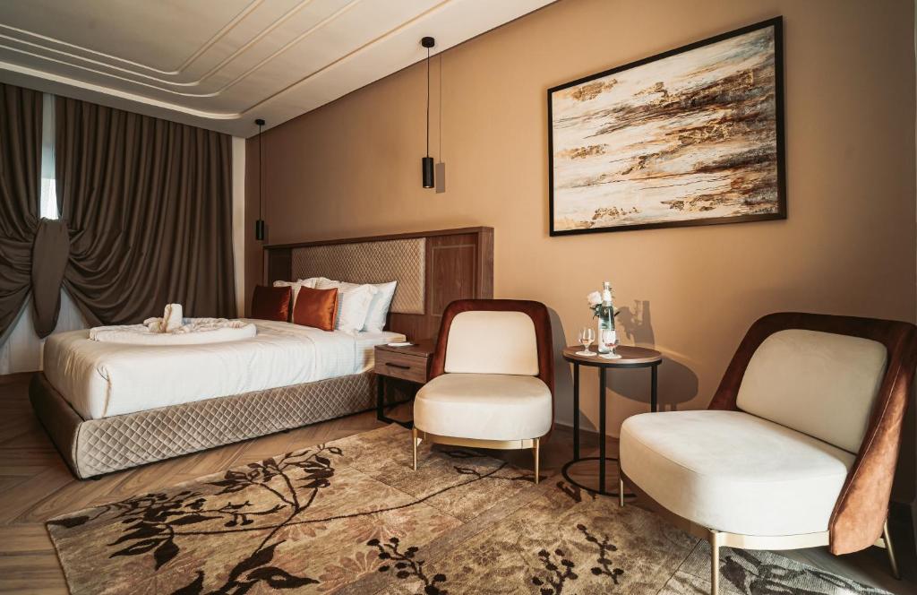 um quarto de hotel com uma cama e duas cadeiras em City Hotel by Waves em Kenitra
