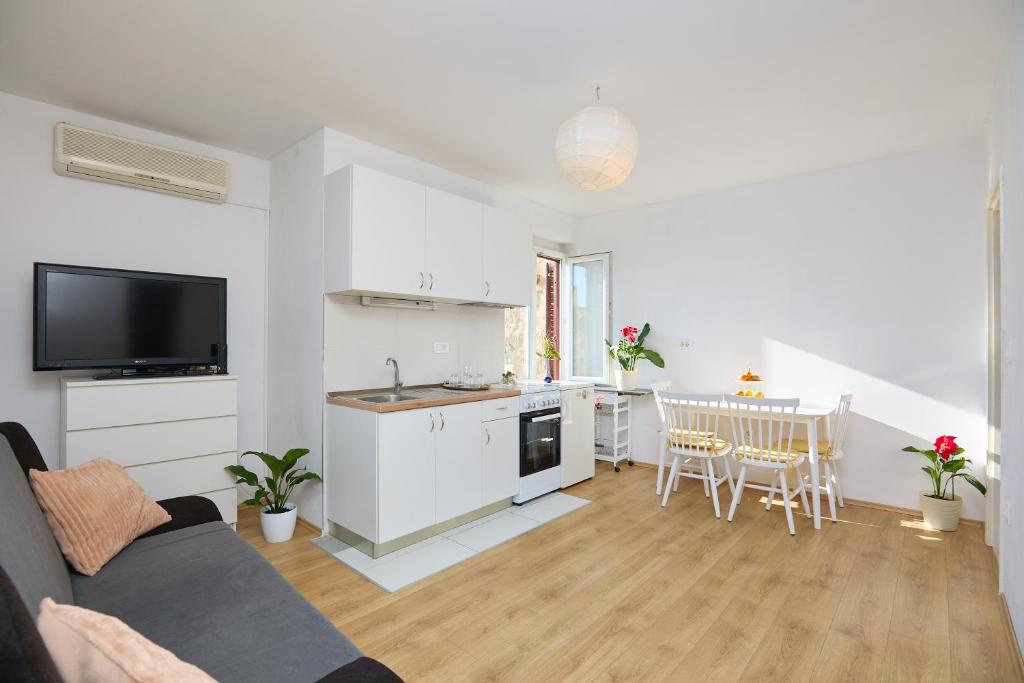 a white living room with a kitchen and a table at Apartment Mare in Dubrovnik
