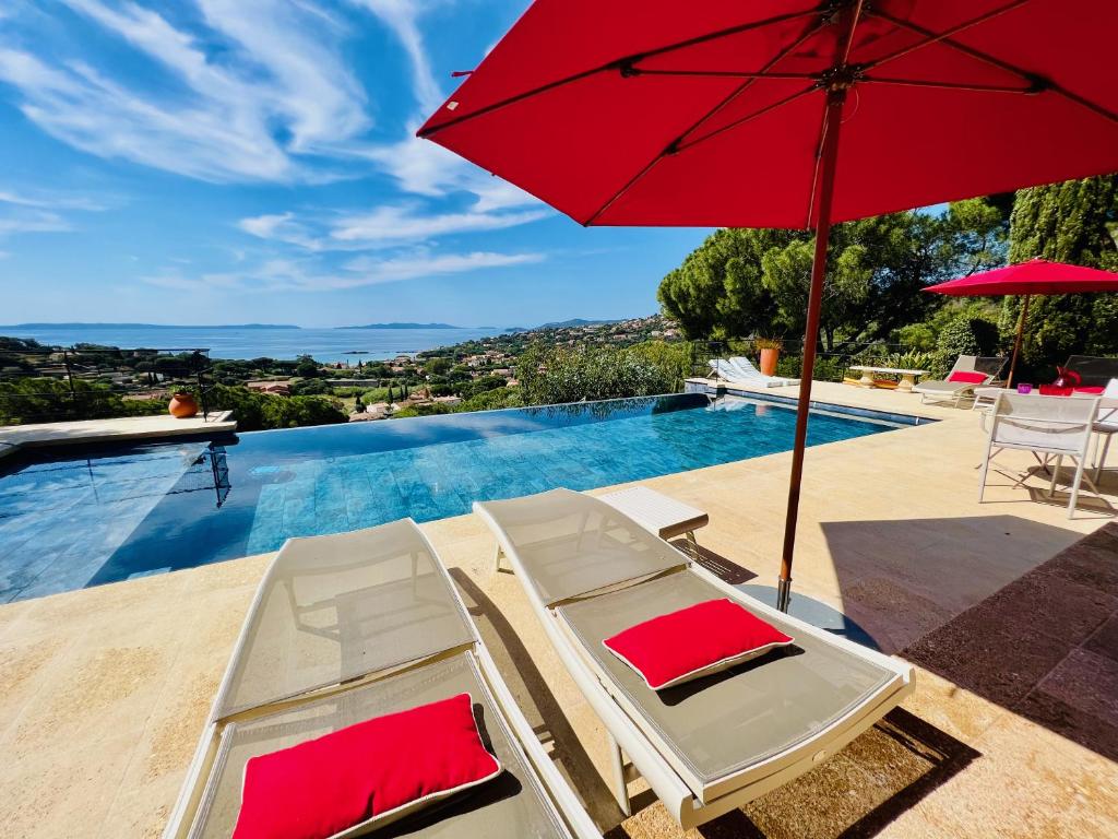 2 sillas y sombrilla junto a la piscina en Villa Thalassa Art' B&B en Le Lavandou