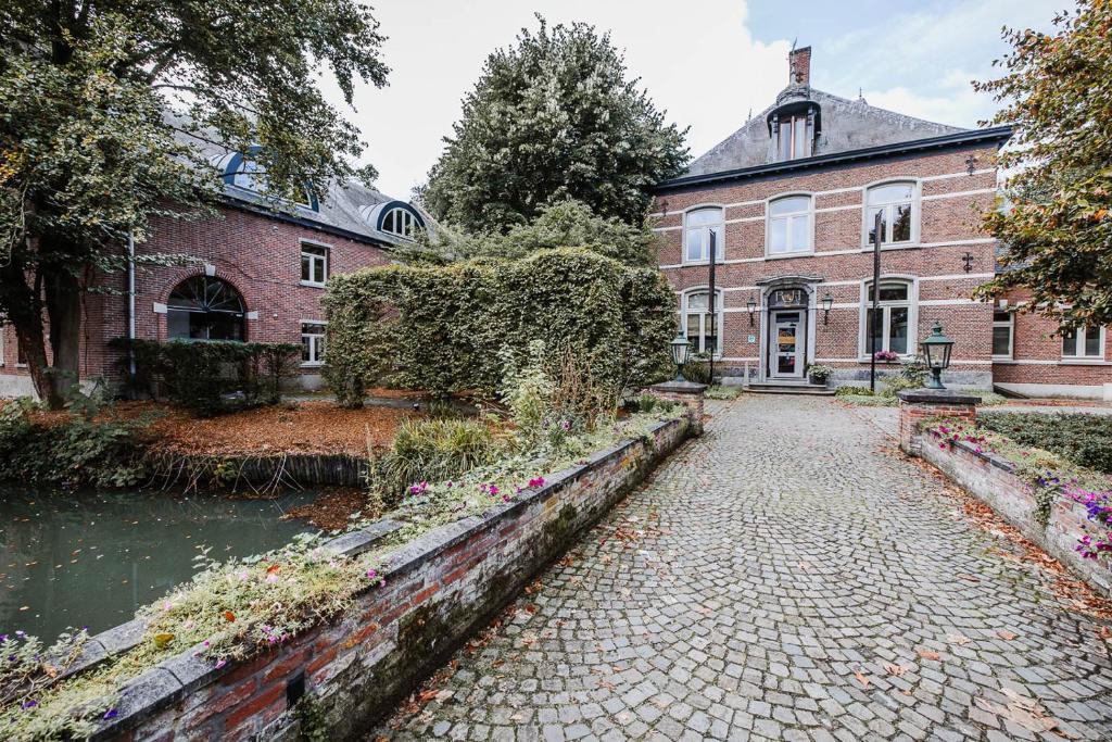 a brick building with a canal in front of it at B&B Roosendaelhof in Geel