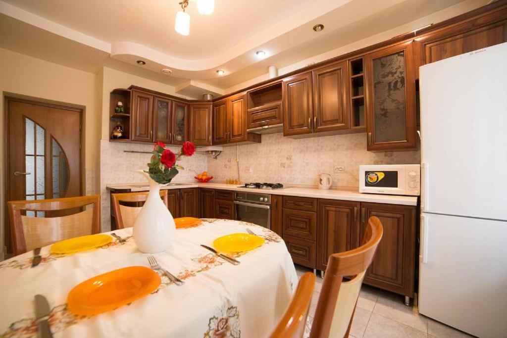 a kitchen with a table and a white refrigerator at новобуд 2 кімнати Вернадського 8 in Lviv