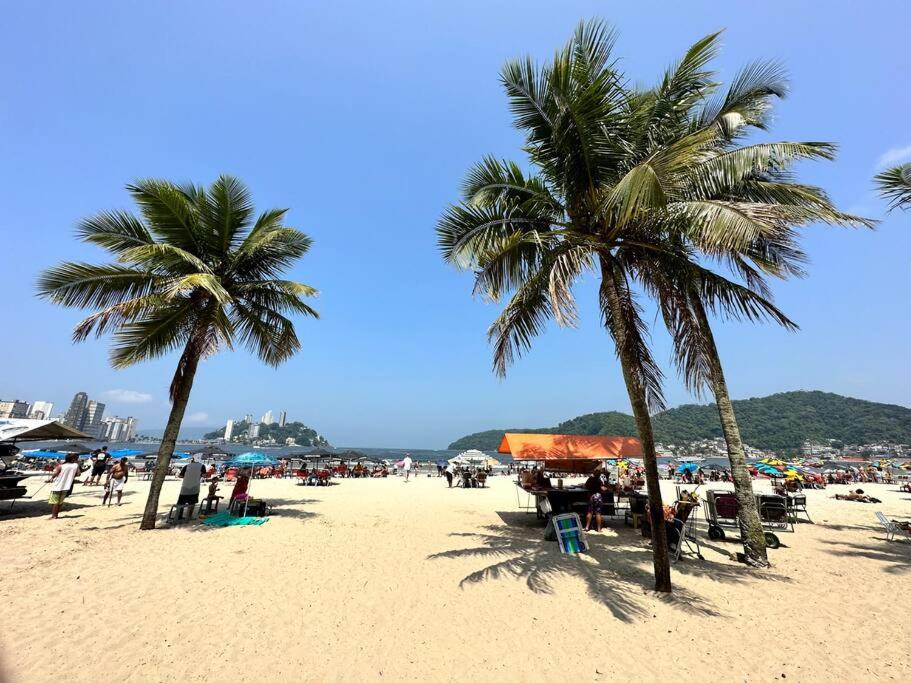 uma praia com palmeiras e uma multidão de pessoas em Apto 50m da praia Gonzaguinha São Vicente Edifício Estrela do Mar em São Vicente