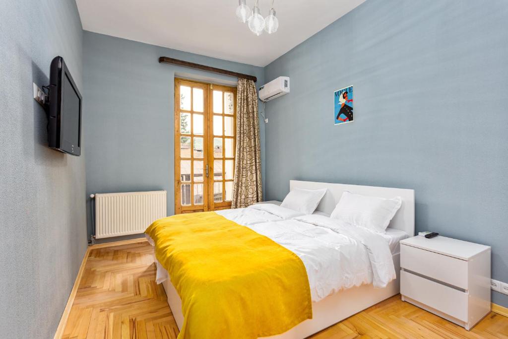 a bedroom with a bed with a yellow blanket at Sunny Hotel Tbilisi in Tbilisi City
