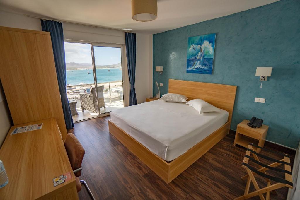 a bedroom with a bed and a view of the ocean at Blue Marlin Hotel in Mindelo