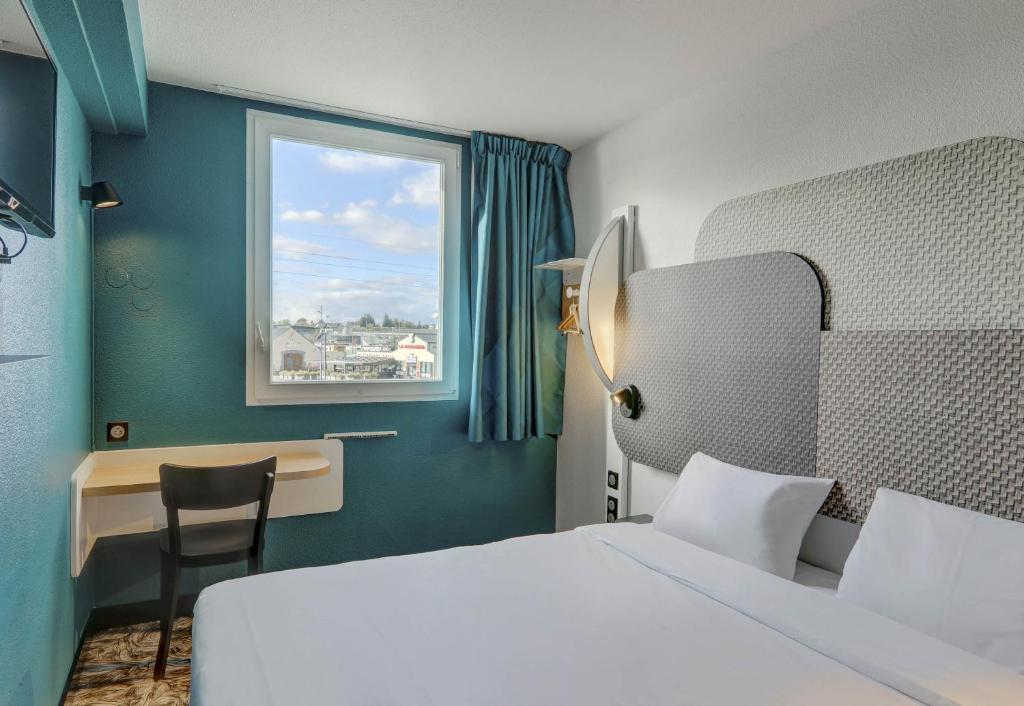 a bedroom with a bed and a desk and a window at B&B HOTEL Montluçon Saint-Victor in Saint-Victor