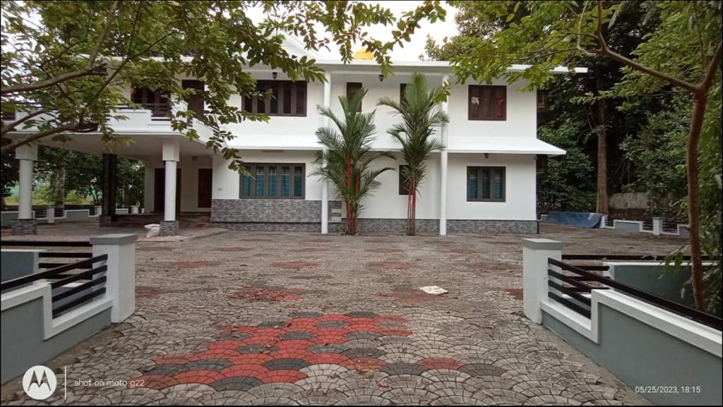 a white house with a courtyard in front of it at Kayyany's Villa - A Large Family Home in Kanjirapalli