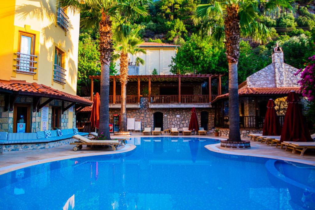 a large swimming pool with palm trees and a building at Dores Residence in Turunc