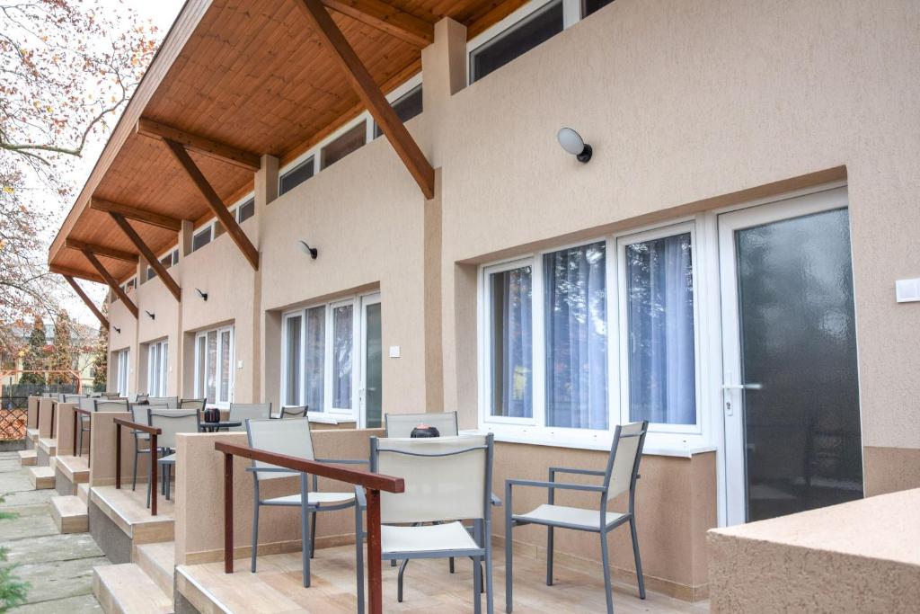 une rangée de chaises et de tables avec fenêtres dans l'établissement Lakeside Apartmanház Soltvadkert, à Soltvadkert