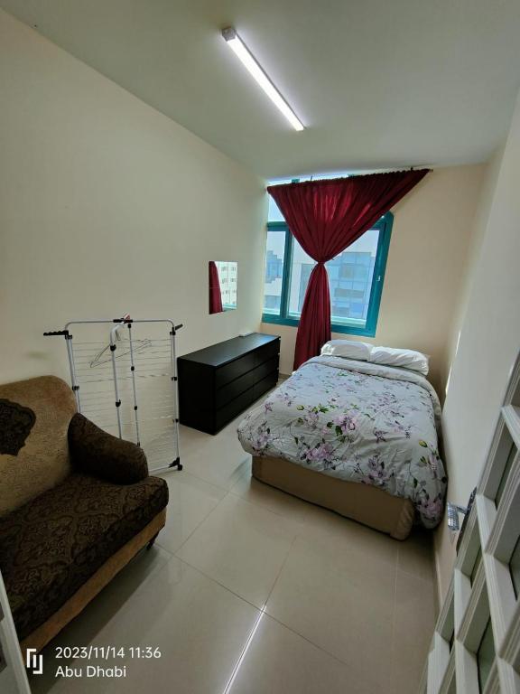 a bedroom with a bed and a couch and a window at Bedroom 4 in Abu Dhabi