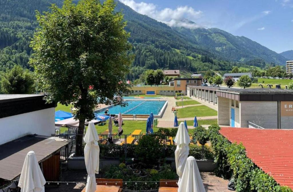 a resort with a swimming pool and some white umbrellas at Gästezimmer Lercher in Sankt Veit im Pongau