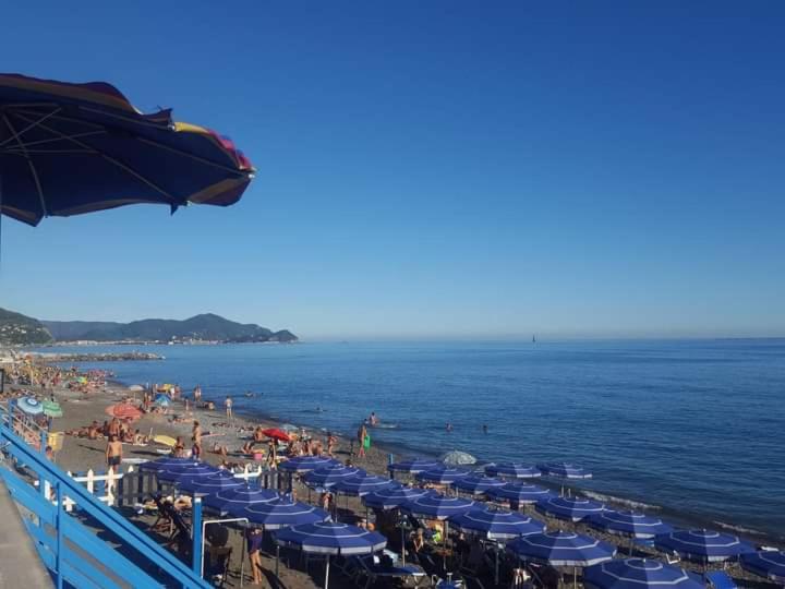 une plage avec des parasols bleus et des foules de gens dans l'établissement TRILOCALE LAVAGNA con box comoda al mare e negozi, à Lavagna