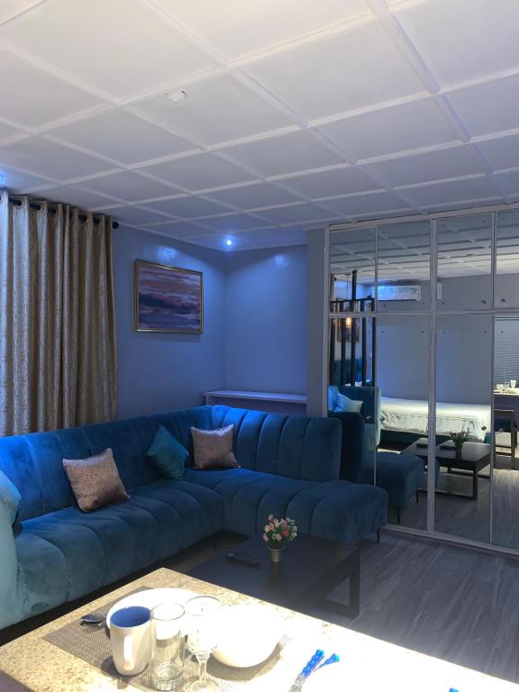 a living room with a blue couch and a bedroom at Teal Snug Open-Plan Studio Unit in Lekki Phase 1-Netflix, Wi-Fi, 24-7 Light, Washer, Kitchen in Lagos