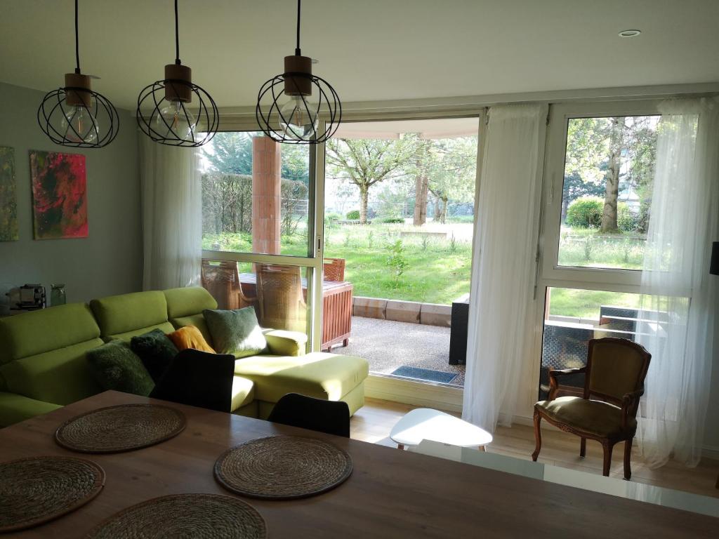 a living room with a green couch and a table at Bel Appartement avec jardin privé au calme in Strasbourg