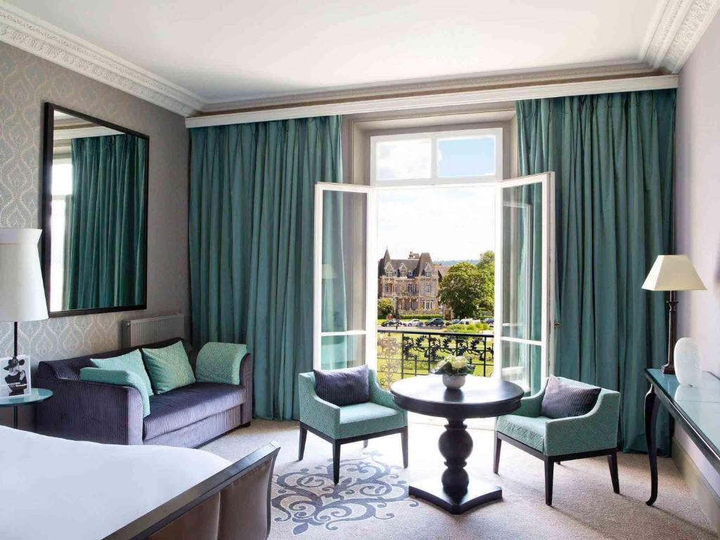a hotel room with a bed and a large window at Le Grand Hotel de Cabourg - MGallery Collection in Cabourg