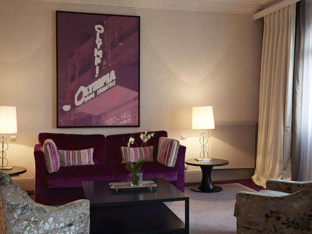 a living room with a purple couch and a table at Le Grand Hotel de Cabourg - MGallery Collection in Cabourg