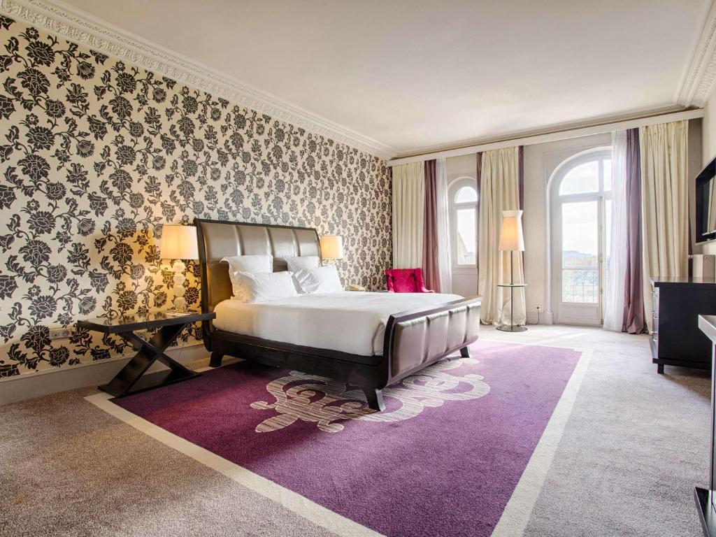 a bedroom with a large bed and a purple rug at Le Grand Hotel de Cabourg - MGallery Collection in Cabourg