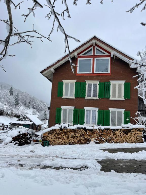 a house with green and red shutters in the snow at Private Room in an old Farmhouse near Vaduz in Sevelen