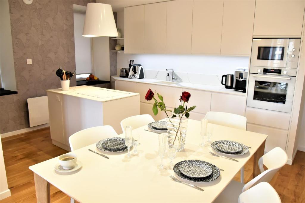 a white kitchen with a white table and chairs at La Maison du Quai Triplex de charme 4 étoiles en hyper centre avec SPA in Landerneau