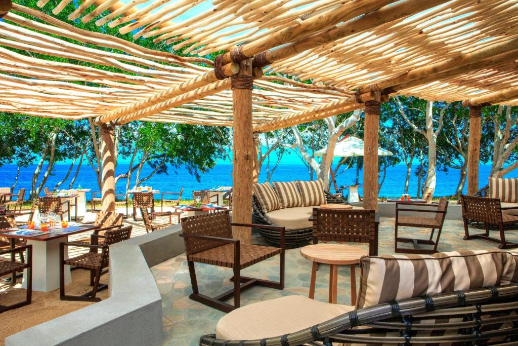 a patio with tables and chairs and the ocean at Sheraton New Caledonia Deva Spa & Golf Resort in Bourail