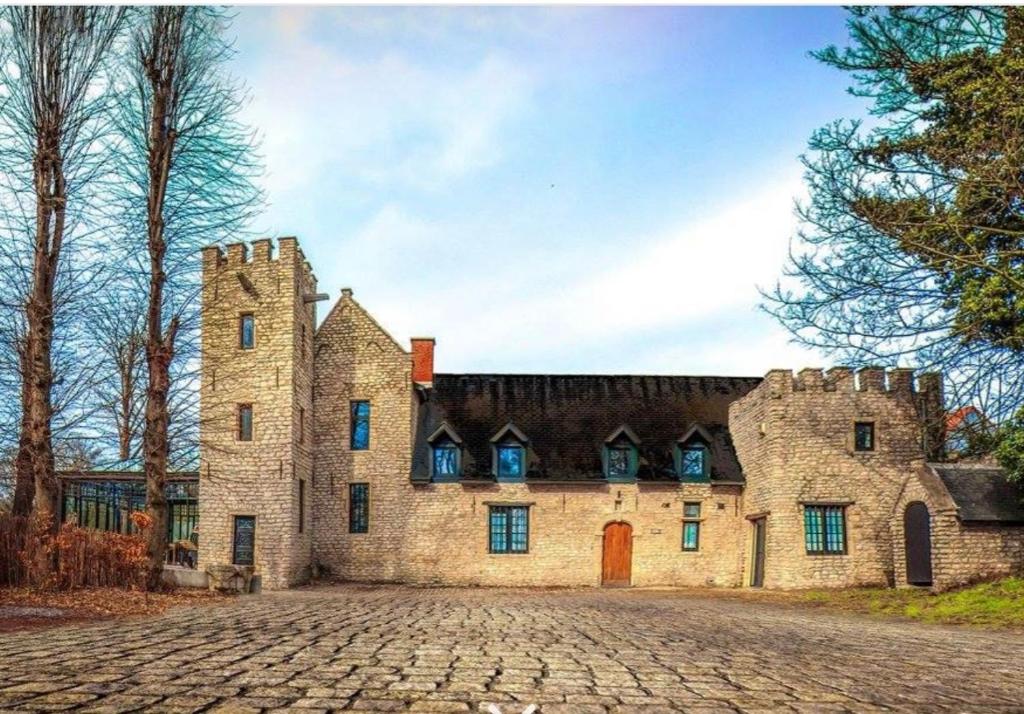 un antiguo castillo con una calle adoquinada delante de él en Elinoa, en Machelen