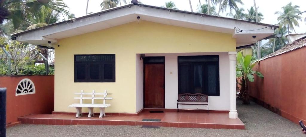 a small yellow house with a white bench in front of it at Villa Mare in Wadduwa