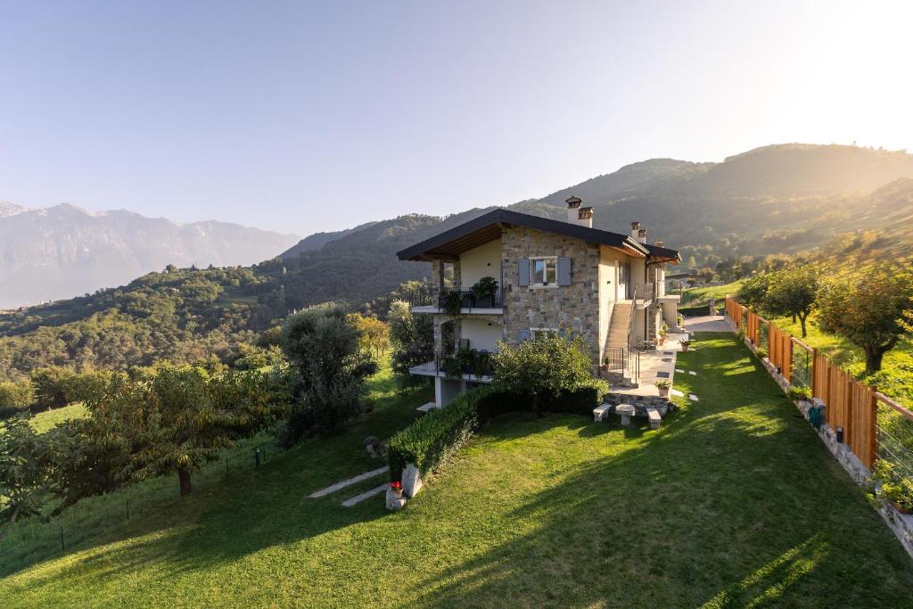 ein Haus auf einem Hügel mit Bergen im Hintergrund in der Unterkunft Mos Country House in Tremosine sul Garda