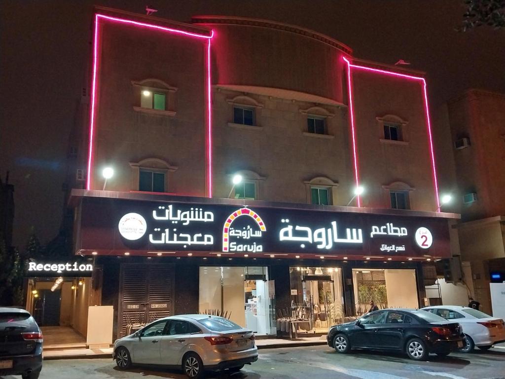 Un edificio con coches aparcados delante. en Nuzul Altoot Apartments نزل التوت, en Riad