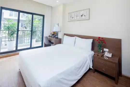 une chambre avec un grand lit blanc et une fenêtre dans l'établissement Tigon Hotel - 148 Nguyễn Chánh HN by - BAY LUXURY, à Hanoï