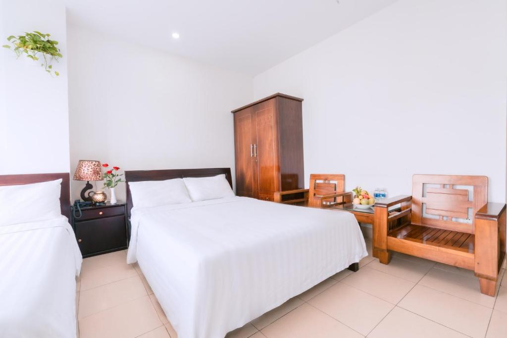 a bedroom with a white bed and a wooden cabinet at Lotus Rock Hotel Đà Nẵng in Da Nang