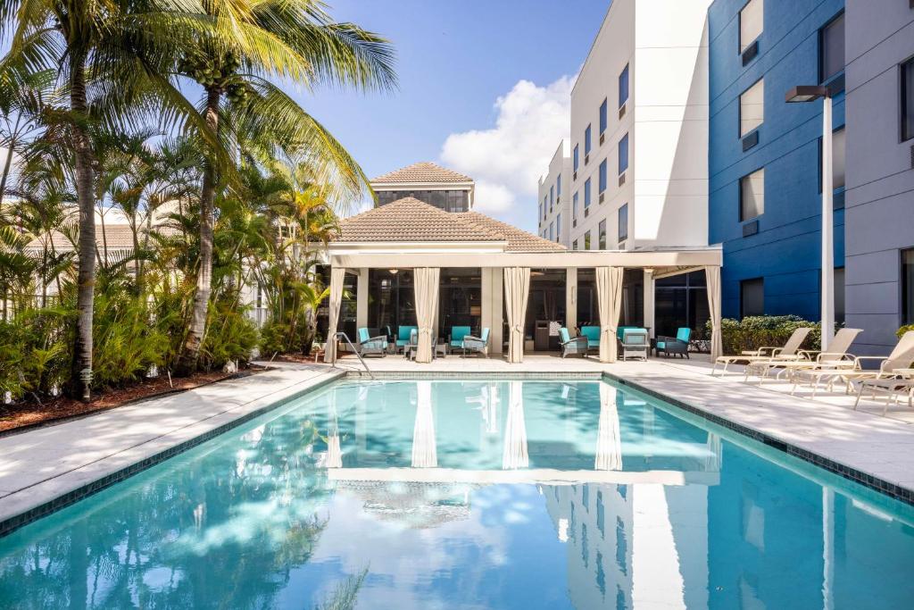 Hilton Garden Inn West Palm Beach Airport في ويست بالم بيتش: مسبح امام مبنى مع شرفة