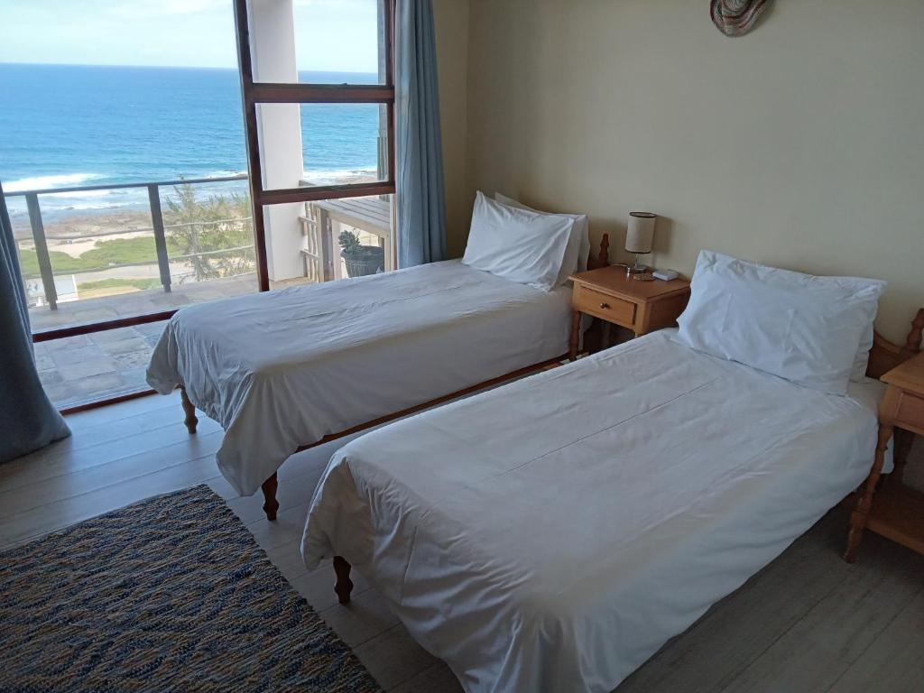 twee bedden in een kamer met uitzicht op de oceaan bij Captain Sunshine Guest House in Jongensfontein