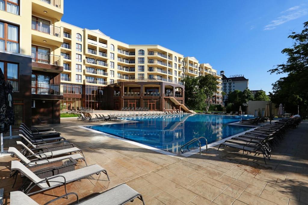 ein großer Pool mit Stühlen und ein Hotel in der Unterkunft Apart Hotel Golden Line in Goldstrand