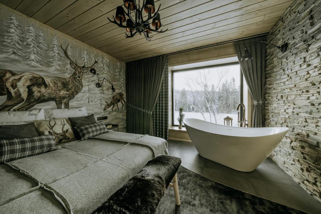 a bathroom with a bath tub and a bed with a window at Luxury Chalet Kajmer in Jurgów