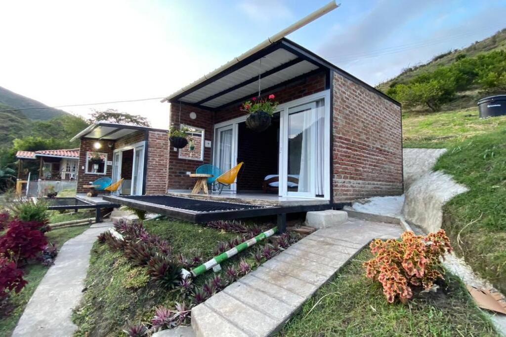 ein winziges Haus auf einem Hügel mit einer Terrasse in der Unterkunft Cabañas “Pacha Mama” in Roldanillo