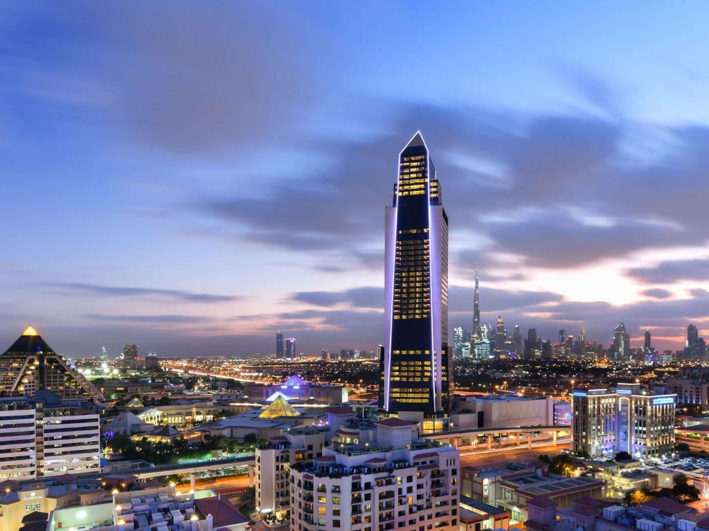 un gratte-ciel haut dans une ville la nuit dans l'établissement Sofitel Dubai The Obelisk, à Dubaï