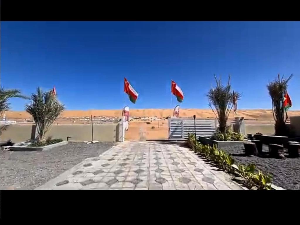 a walkway with flags flying in the desert at alsaif camp in Bidiyah