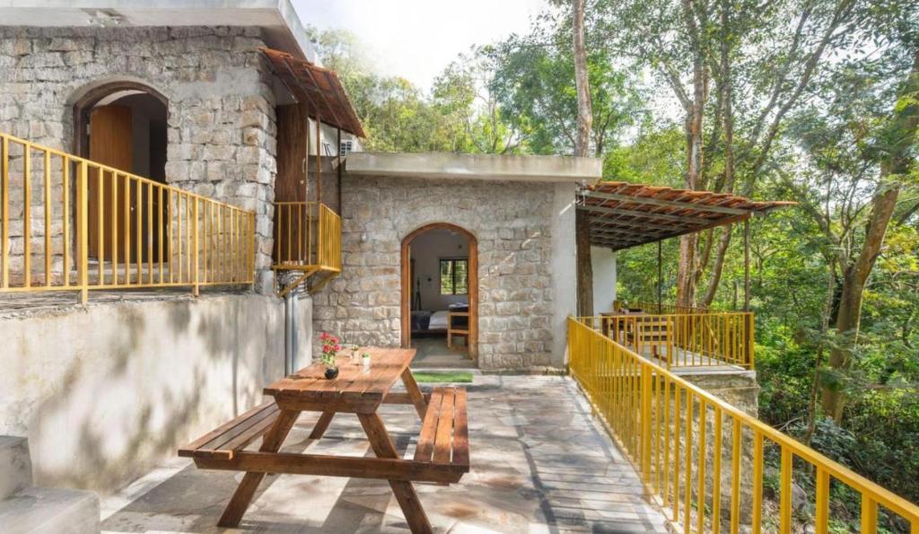 ein Steinhaus mit einem Holztisch auf einer Terrasse in der Unterkunft Jungle stay by Bilwa Estate in SanivÄrsante