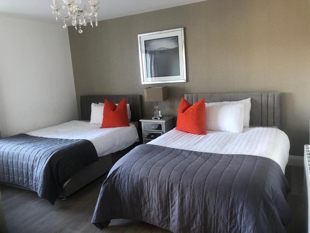 2 camas en una habitación de hotel con almohadas rojas en Oak Tree Lodge, en Westport