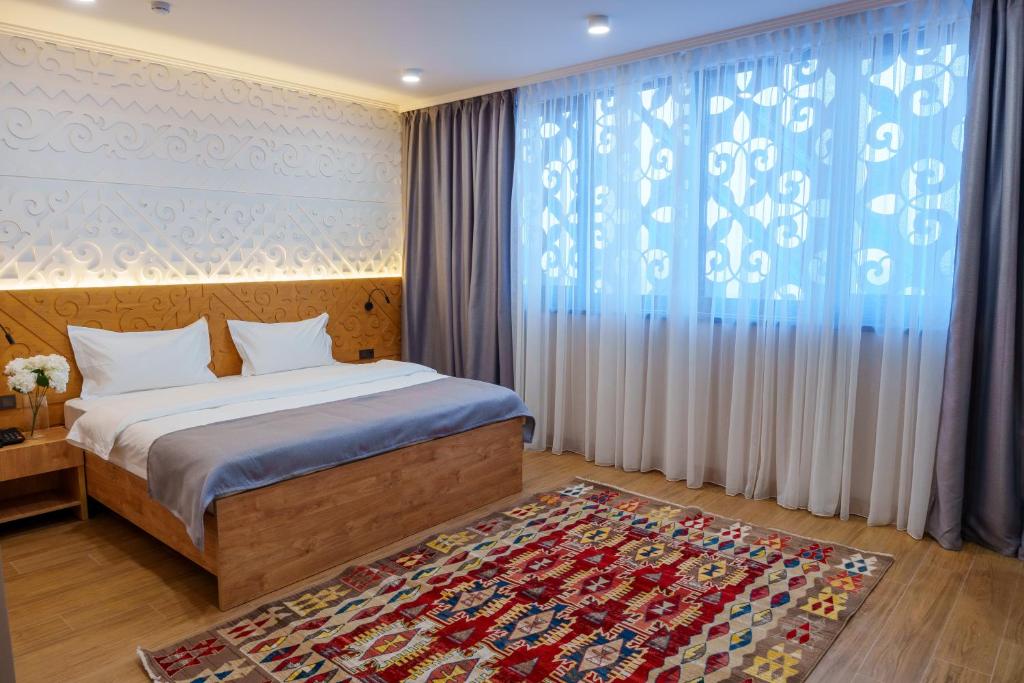 a bedroom with a bed and a large window at Dami Almaty Hotel in Almaty