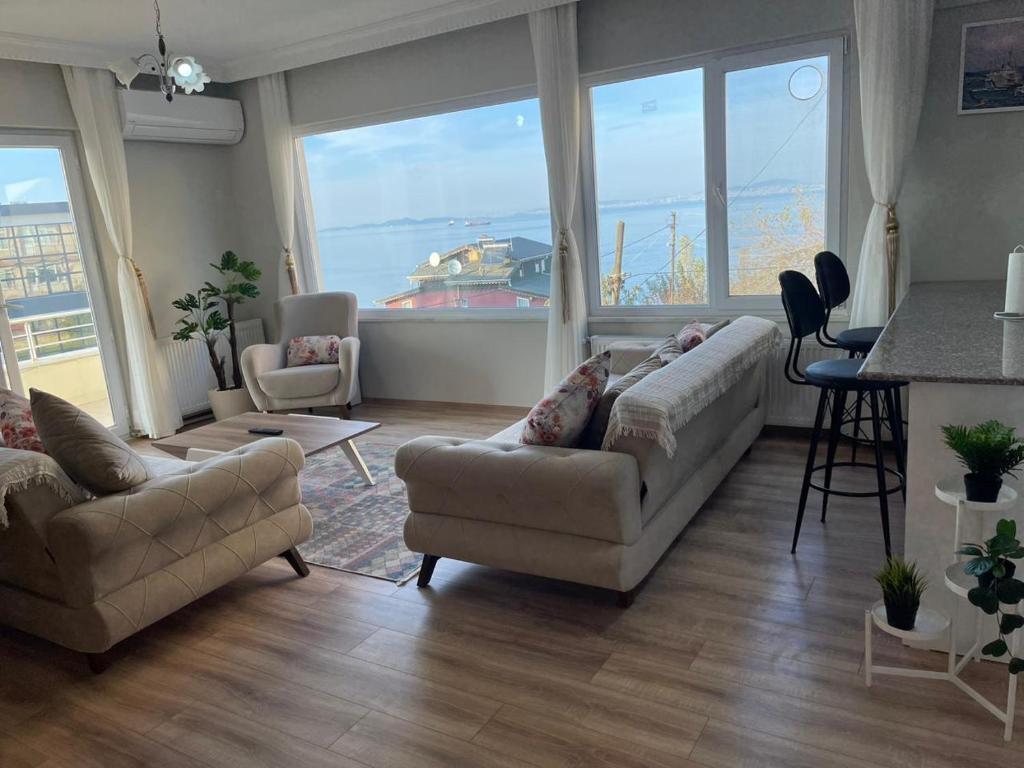 a living room with two couches and a kitchen with a view of a boat at Yalova Apartments in Yalova