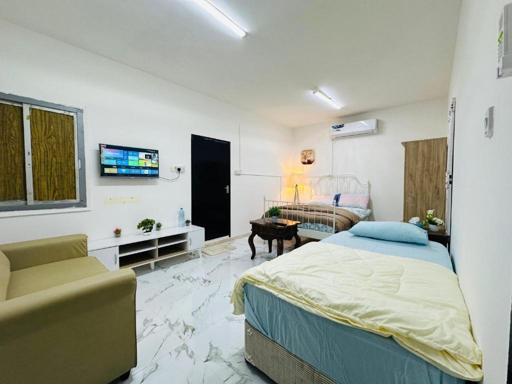 a bedroom with a bed and a couch and a tv at Comfy Studio Apartment in Abu Dhabi