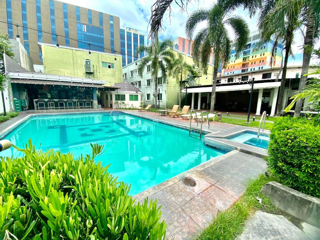 a large blue swimming pool with palm trees and buildings at Hotel Euroasia By BLUEBOOKERS in Angeles