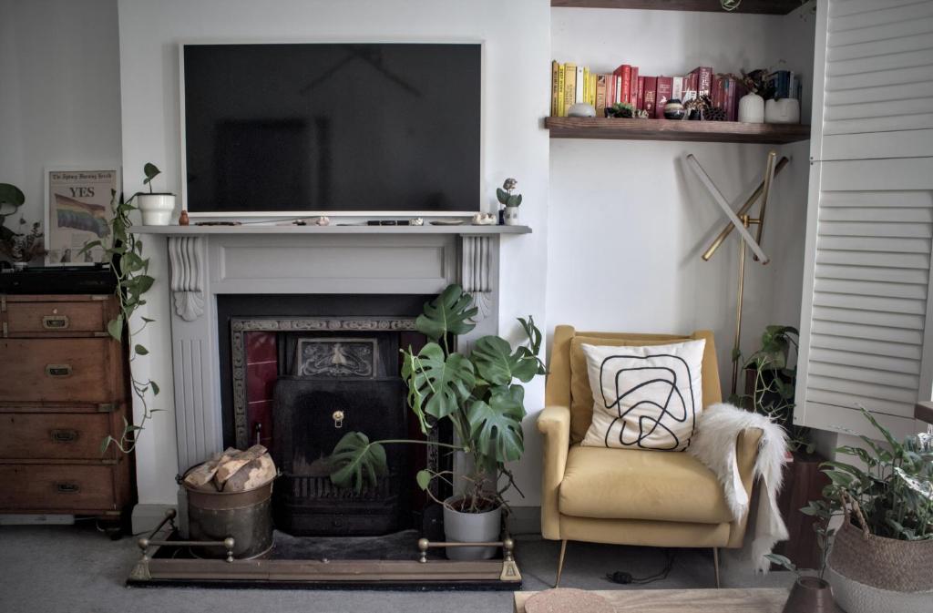 a living room with a fireplace with a chair and a television at The Rose Terrace - 2BD Home Kentish Town in London