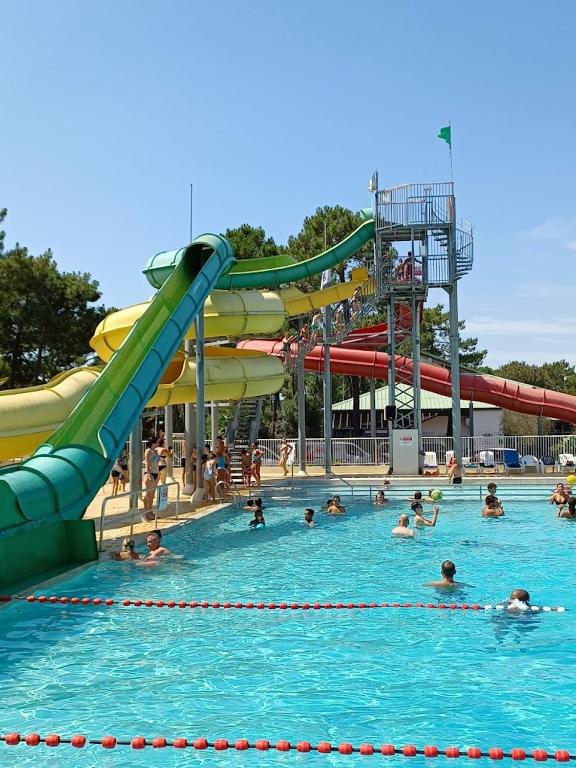 people in a swimming pool with a water slide at Mobil Home 6 personnes camping 4 etoiles Bonne Anse la Palmyre in Les Mathes