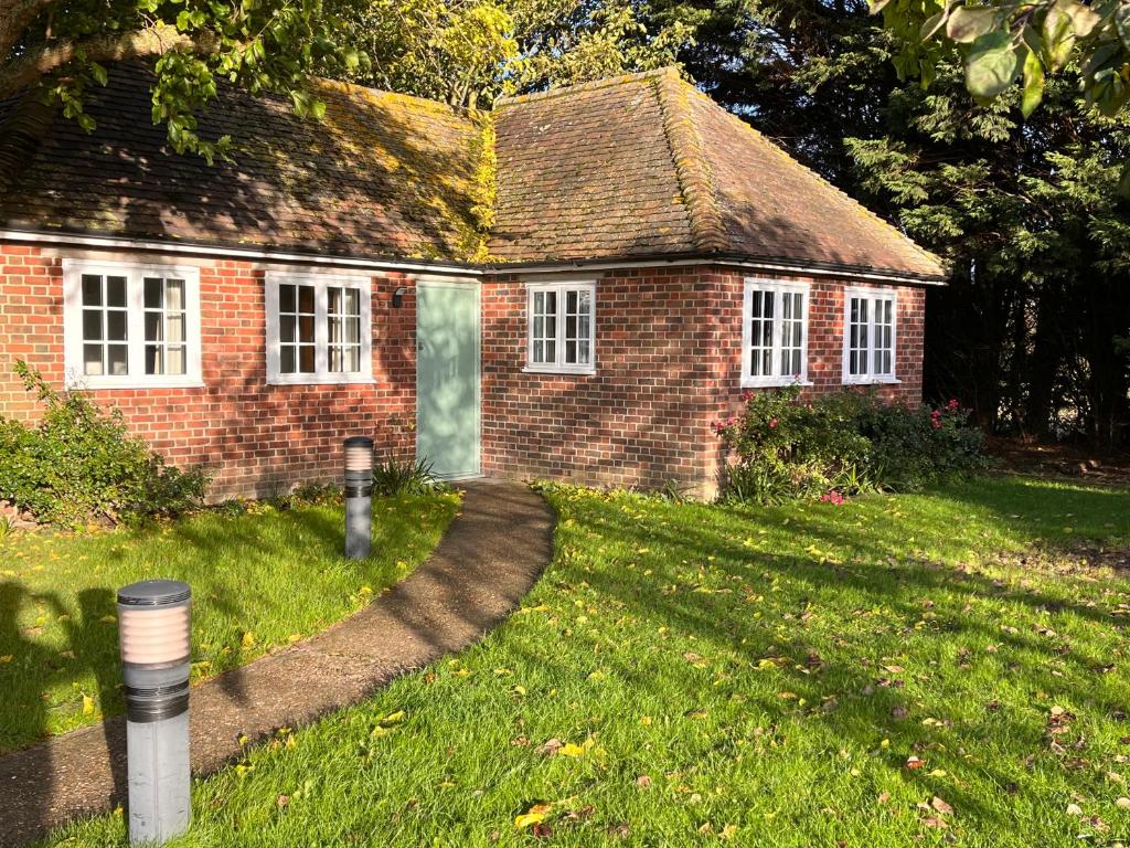 a small brick house with a grass yard at Green Cottage in grounds of Grade II* Frognal Farmhouse in Sittingbourne