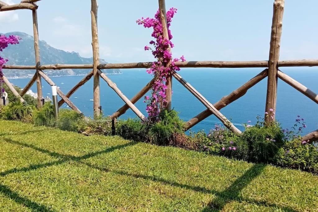 a fence with flowers on the grass with the ocean in the background at Villa Alba - Rubino in Amalfi