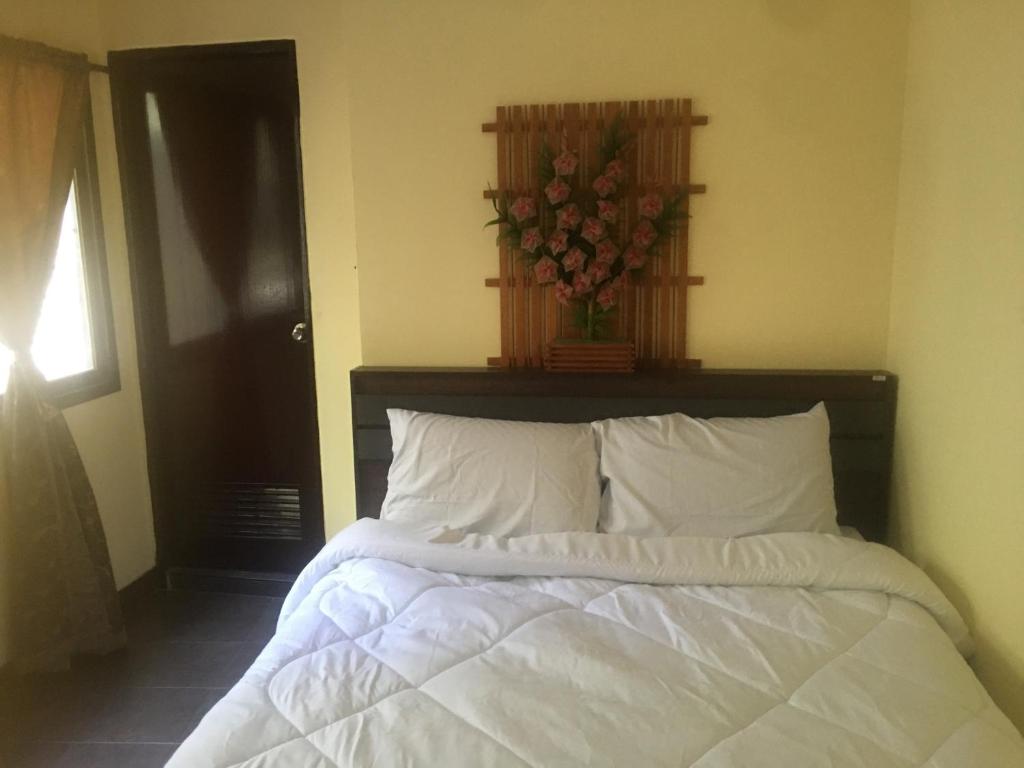 1 dormitorio con 1 cama blanca y un jarrón de flores en GUNG Apartment, en Pattaya South