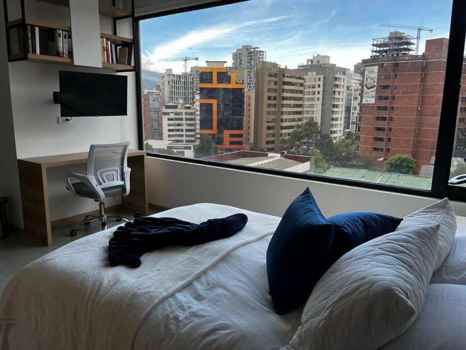 een slaapkamer met een bed en een groot raam bij Estudio luminoso con balcón in Quito